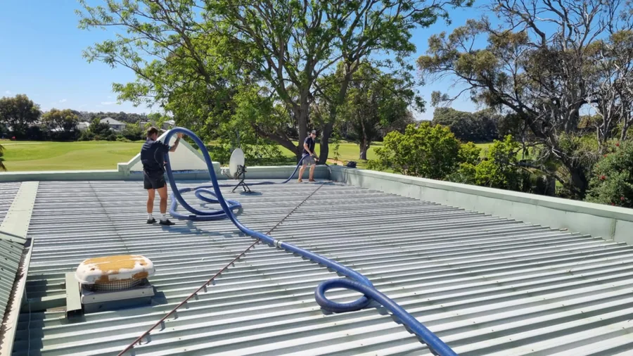 Worker vacuum cleaning a large commercial roof